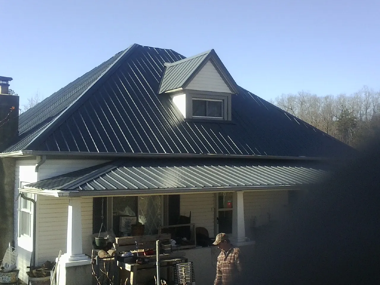 Dark blue standing seam metal roof with a dormer above a front porch in East Norwich