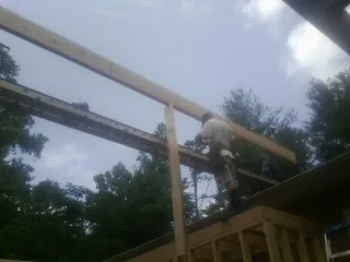 Carpenter setting a ridge beam over a new addition frame — Ice Dam Removal by Roofing Brothers in East Norwich