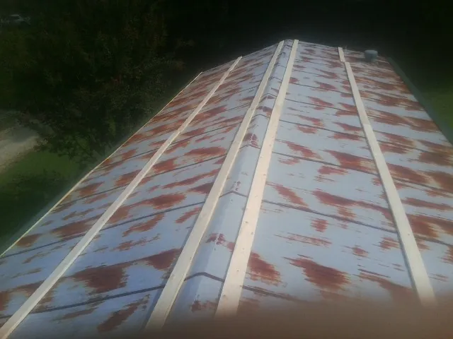 Rusted metal roof panels with new wood purlins before replacement — Storm Damage Roof Repair in East Norwich by Roofing Brothers