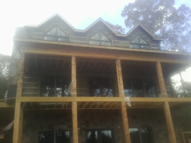Dormers and porch framing on a large log home under construction — Roof Coating work by our crew in East Norwich