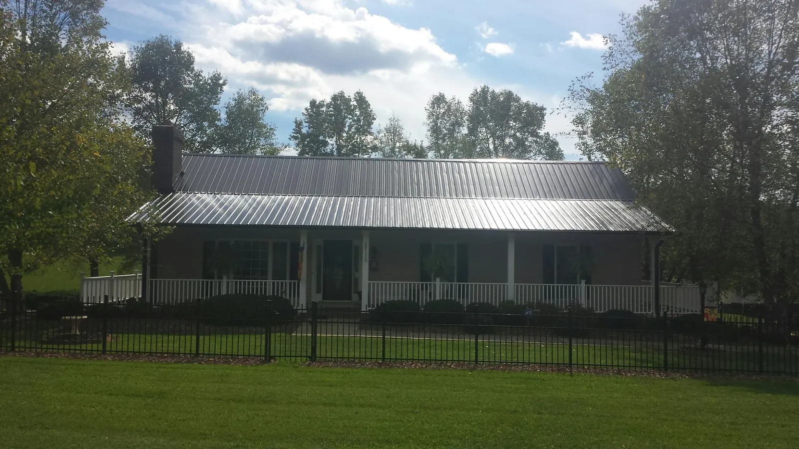 Gray metal roof on a brick ranch with a full width front porch — Gutter Guard Installation work by our crew in East Norwich
