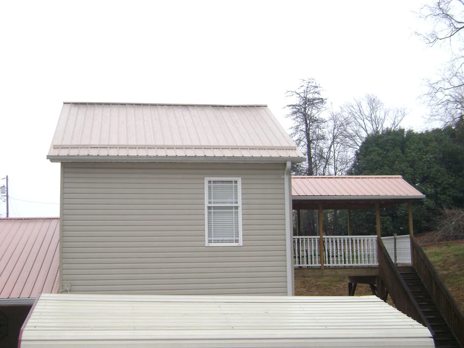 Tan metal roofs on a two story addition and attached porch, from a Roof Replacement job in East Norwich