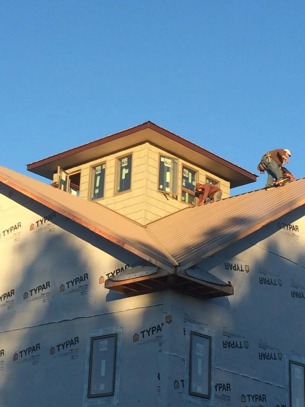 Roofers working around a rooftop cupola on a new metal roof at sunset — Roof Waterproofing in East Norwich by Roofing Brothers
